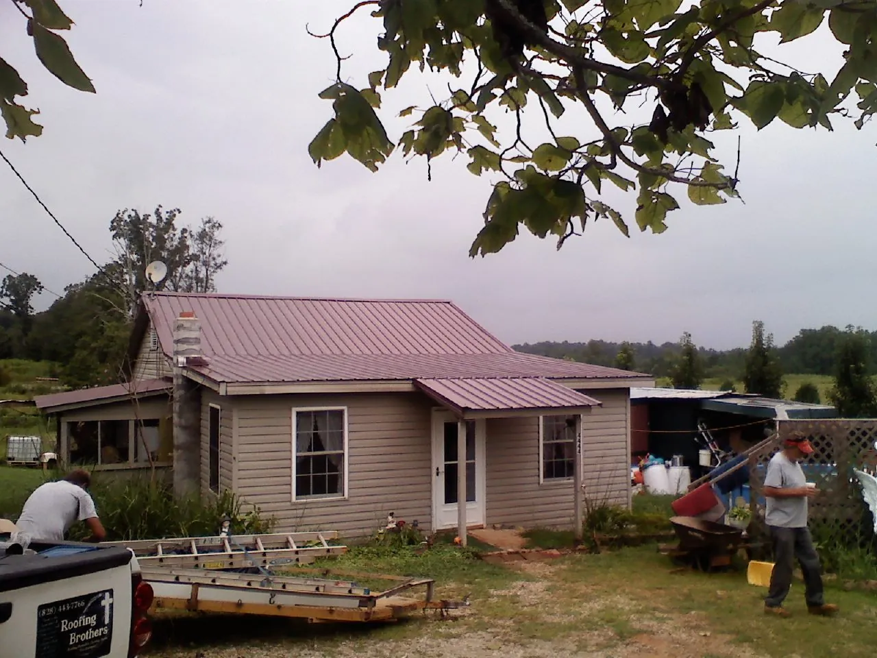 Crew finishing a mauve metal roof on a small farmhouse in Polk