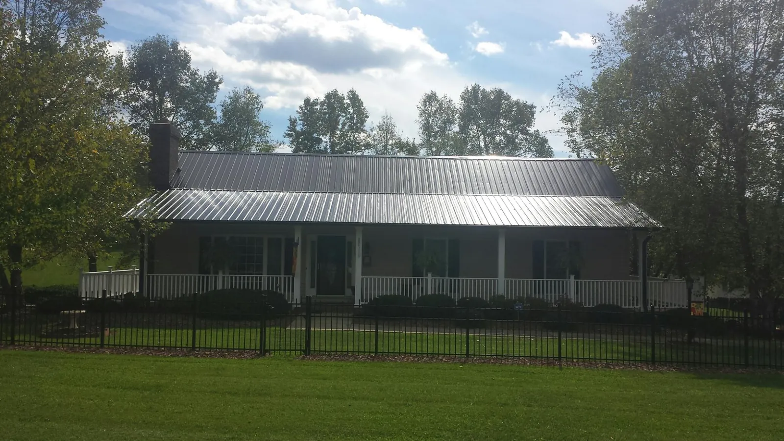 Gray metal roof on a brick ranch with a full width front porch — Gutter Guard Installation work by our crew in Polk